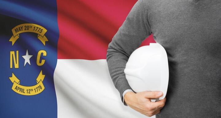 Man with a hard hat standing in front of the North Carolina state flag