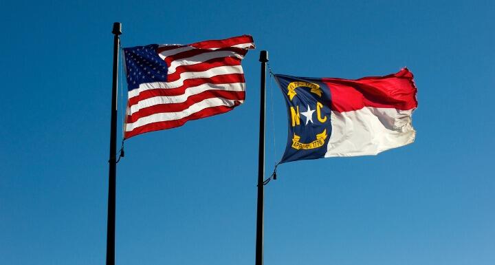 North Carolina and US flags against blue sky