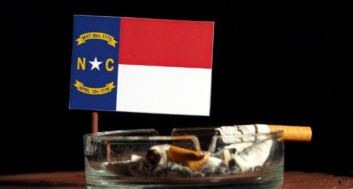 North Carolina flag with burning cigarette in ashtray