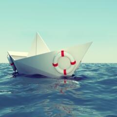 A paper boat tossed on a blue sea