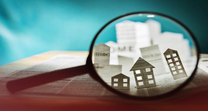Magnifying glass focusing on houses cut out of paper