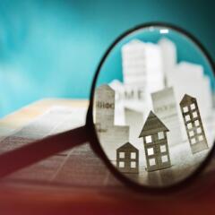 Magnifying glass focusing on houses cut out of paper