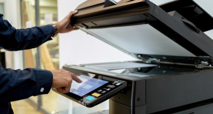 A person scanning documents on a large freestanding scanner-copier-printer machine