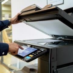 A person scanning documents on a large freestanding scanner-copier-printer machine