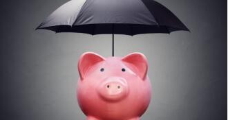 A pink ceramic piggy bank under a black umbrella signifying financial safety net