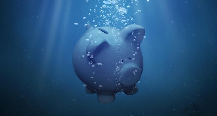 A piggy bank sinking under blue water