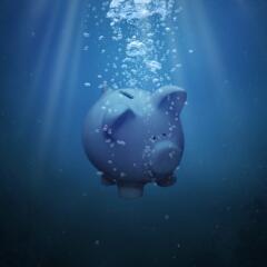 A piggy bank sinking under blue water