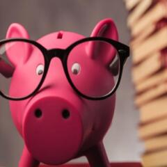 Piggybank wearing glasses standing beside books