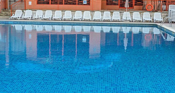 Inground pool with white chairs along surround deck