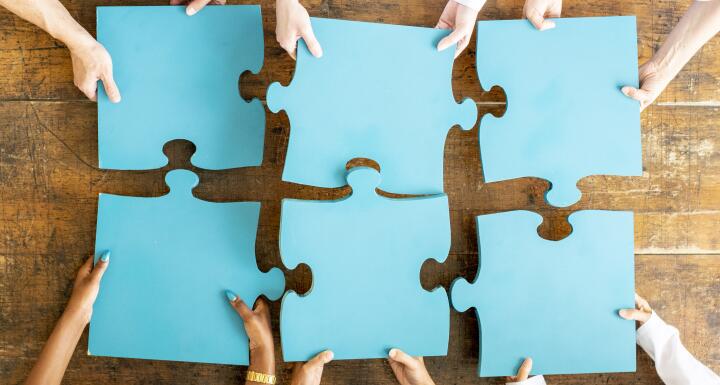 Six blue puzzle pieces on wooden table