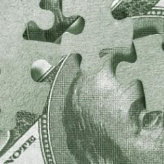 Puzzle pieces laying on top of a bill of money