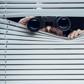 Man peeking through window with binoculars