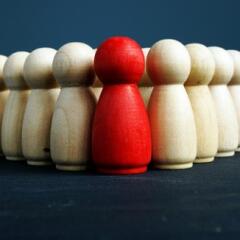 Red wooden figure in front on plain wooden figures
