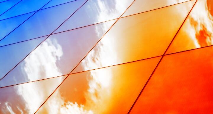 Reflection of sunlight and clouds in exterior of glass office building