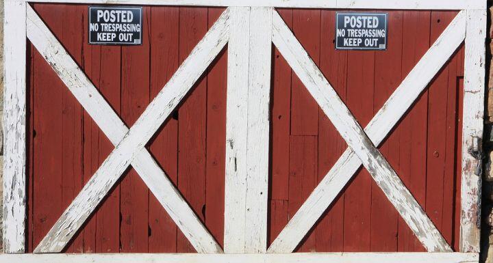Red barn door with no trespassing sign