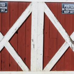 Red barn door with no trespassing sign