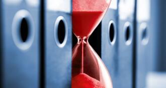 Red sandclock between a row office folders