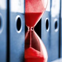 Red sandclock between a row office folders