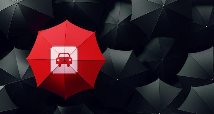 Red umbrella surrounded by black umbrellas,