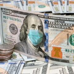 One hundred dollar bill standing upright with a stack of quarters in front of and both are on a layer of one hundred dollar bills