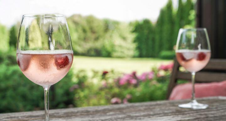 Rose wine glasses on a wooden table at garden