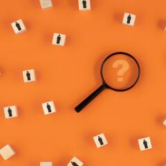Magnifying Glass with Question Mark surrounded by wooden blocks of people icoons