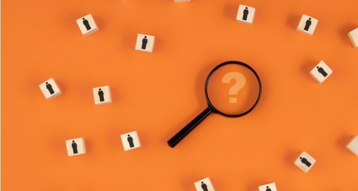 Magnifying Glass with Question Mark surrounded by wooden blocks of people icoons
