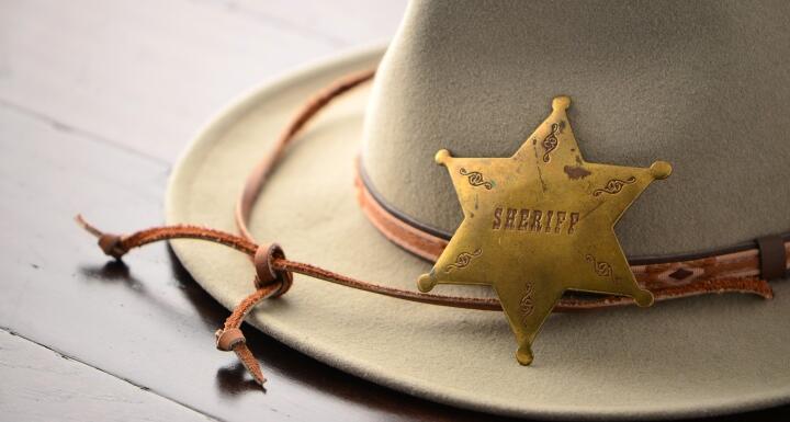 Brown sheriff hat with a badge laying on top