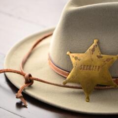 Brown sheriff hat with a badge laying on top