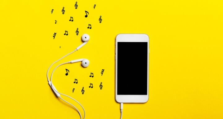 Smartphone, earphones, and music notes on yellow background