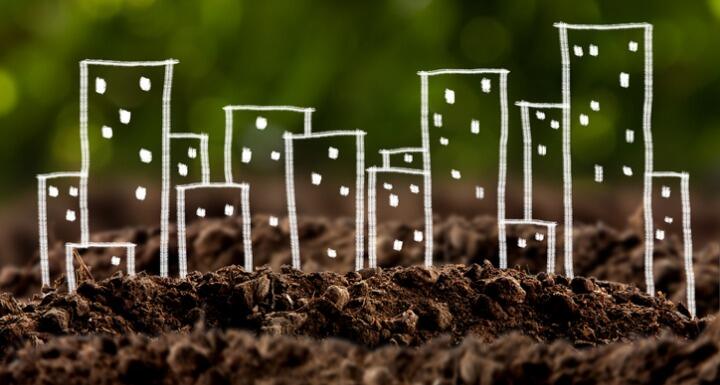 brown dirt with a child's drawing of buildings sitting upon it signifying brownfields redevelopment