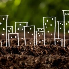 brown dirt with a child's drawing of buildings sitting upon it signifying brownfields redevelopment