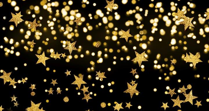 Dozens of sparkling gold stars falling in front of a black back ground