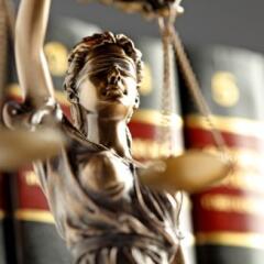 Statue Of Lady Justice In Front Of Row Of Law Books