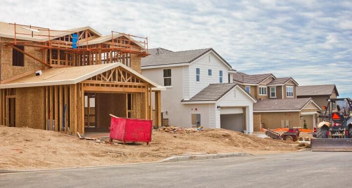 Newly constructed house frame with red trash bin in front