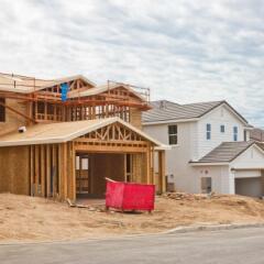 Newly constructed house frame with red trash bin in front