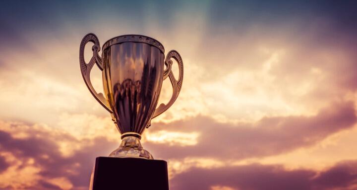 Close up of a gold trophy with a sunset behind it