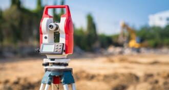 Red and White surveyor's equipment set up on a construction site