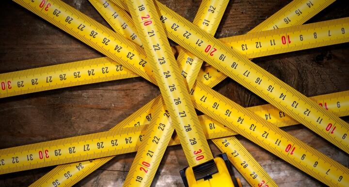 Several measuring tapes arranged in a starburst pattern on a wooden floor