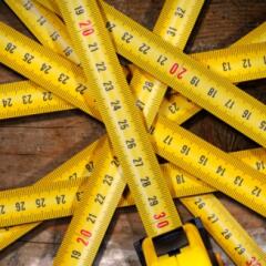 Several measuring tapes arranged in a starburst pattern on a wooden floor