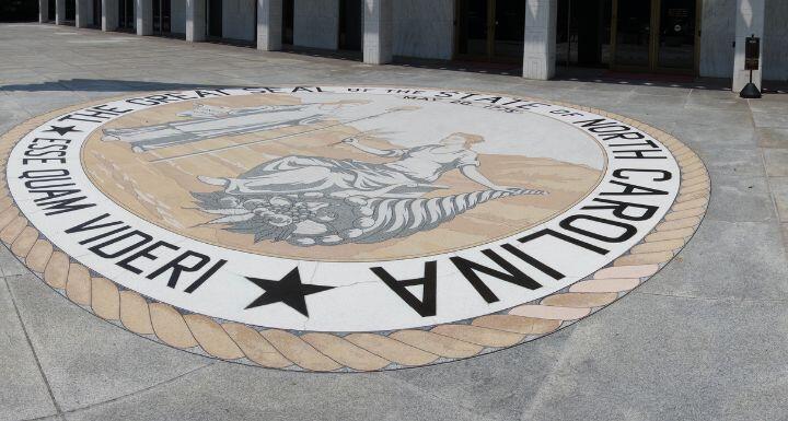 The front entrance of the North Carolina State Legislature building in Raleigh with the state seal and motto 