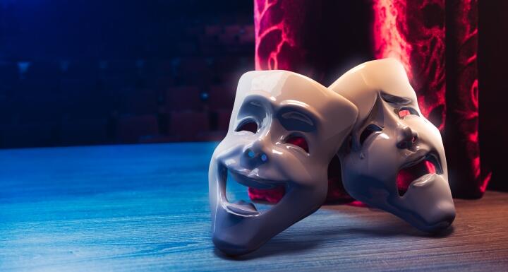 theater mask in front of a red curtain