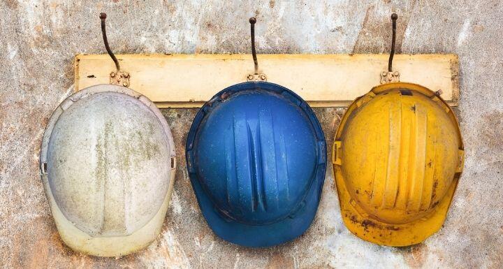 Three construction helmets hanging on a hat-rack