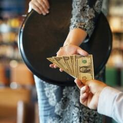 Waitress accepting a tip of multiple dollar bills from a customer