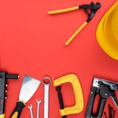 Different Tools and a yellow hard hat on Red Background