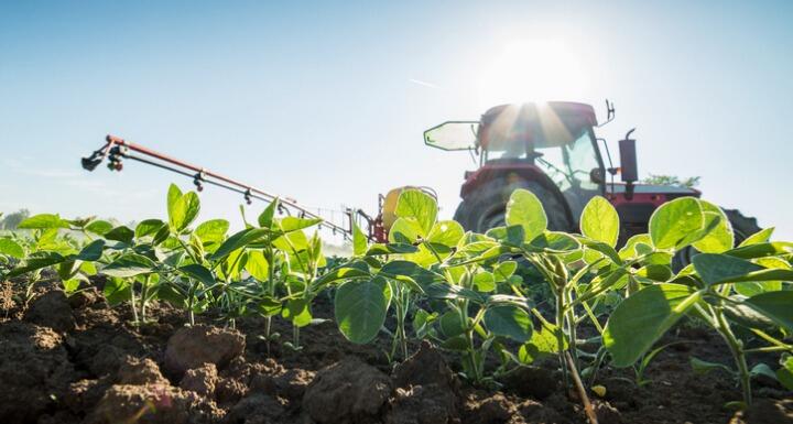 A tractor fertilizing a soybean field