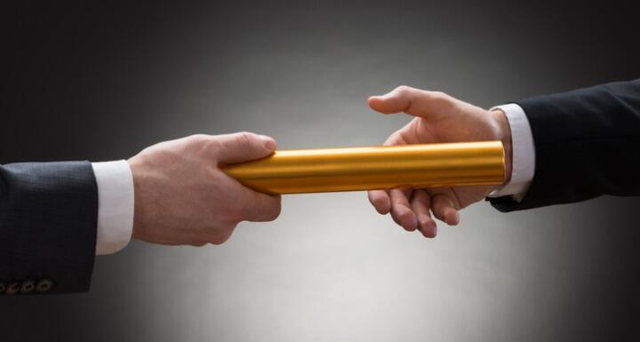 Two Hands Passing A Golden Relay Baton