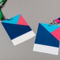 Two colorful conference badges with lanyards on gray background