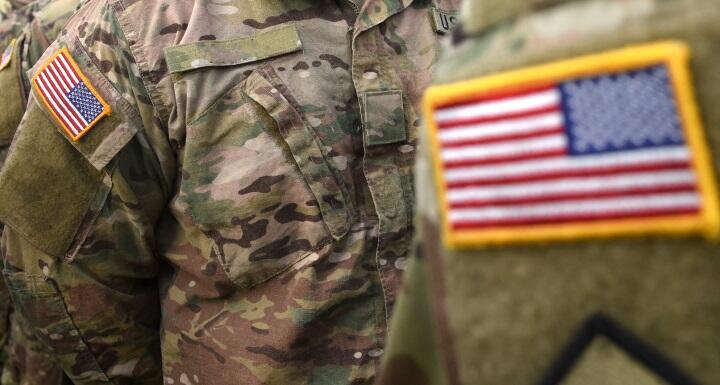 A close up of the American flag on the fatigue uniform of military personnel