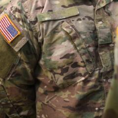 A close up of the American flag on the fatigue uniform of military personnel